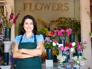 a woman standing in front of a flower shop.